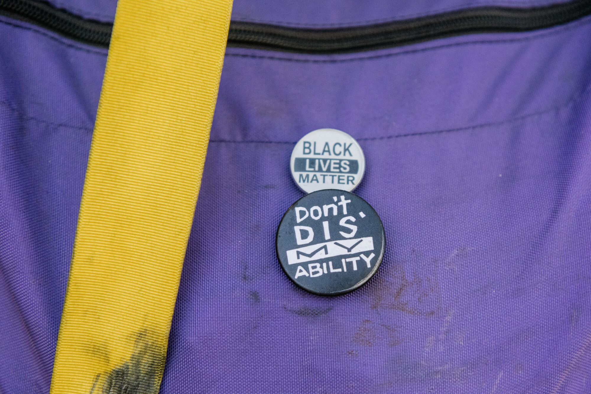Two pins that read Black Lives Matter and don't dis' my disabilty.