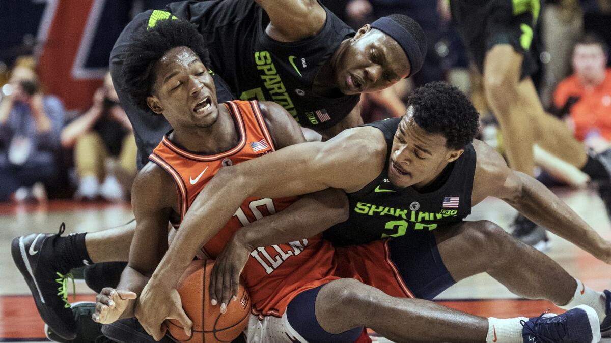 Illinois guard Andres Feliz (10) tries to secure the ball near Michigan State guard Cassius Winston and forward Xavier Tillman (23) during the second half on Tuesday.