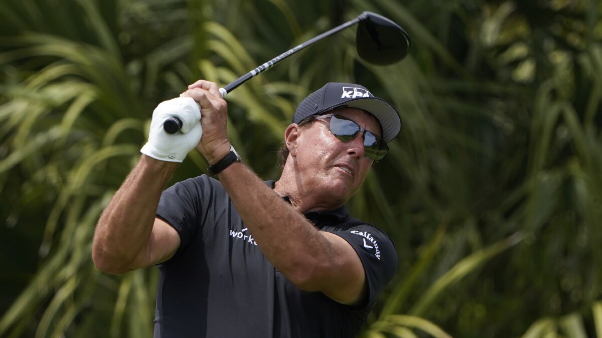 Phil Mickelson watches his tee shot with his golf club above his head