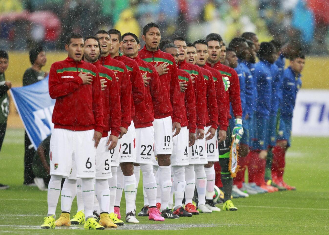 Bolivia's soccer players sing their national anthem in the rain before their 2018 World Cup qualifying soccer match against Ecuador at the Atahualpa stadium in Quito