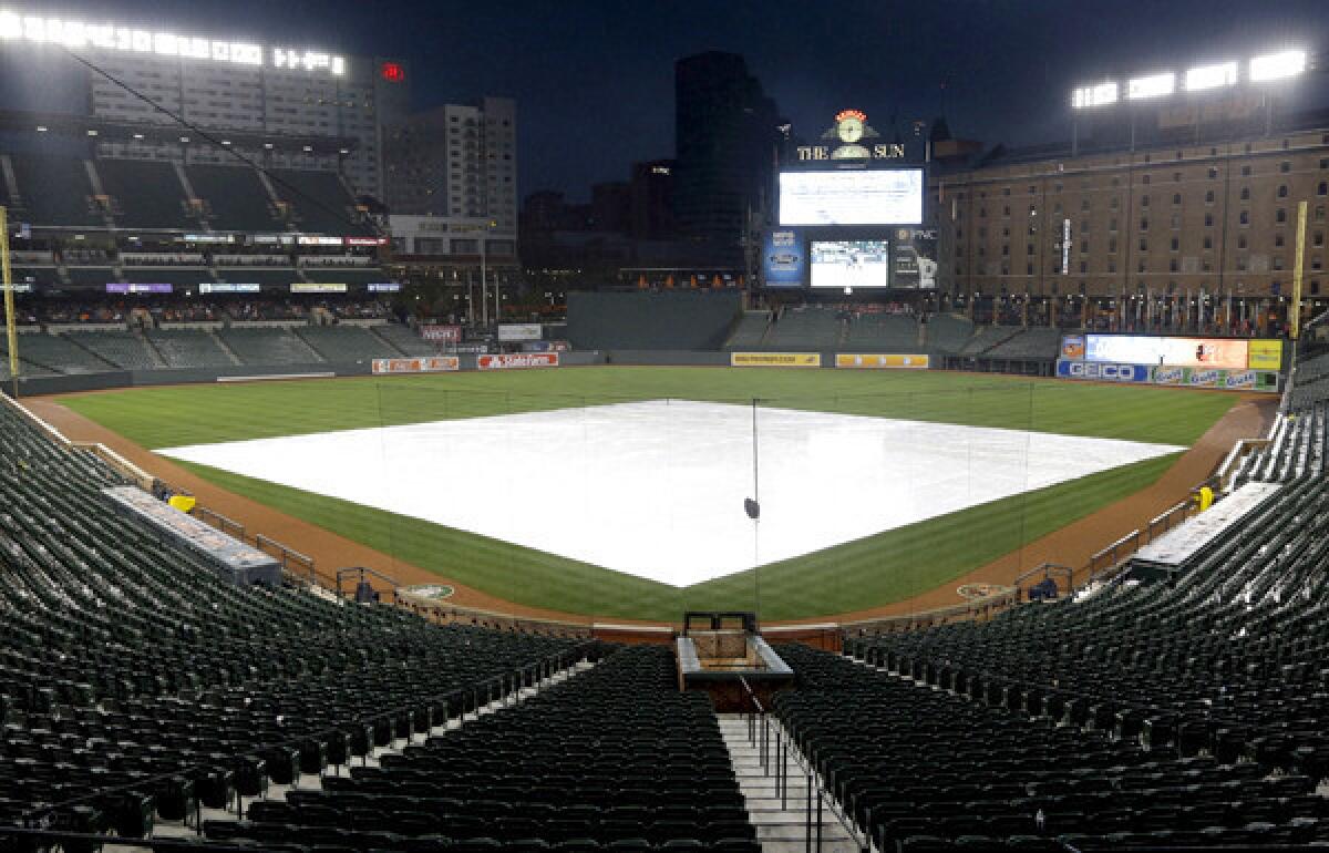 The infield at Camden Yards is covered by a tarp as rain falls Friday evening.