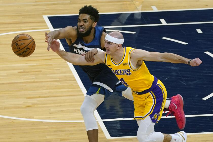 Minnesota Timberwolves' Karl-Anthony Towns, left, and Los Angeles Lakers' Alex Caruso battle for the ball in the first half of an NBA basketball game, Tuesday, Feb. 16, 2021, in Minneapolis. (AP Photo/Jim Mone)