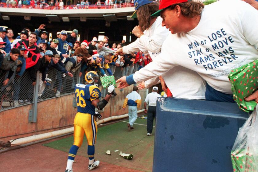 A Los Angeles Rams fan, wearing his sentiments on his shirt, hands safety Anthony Newman a gift after a game against the Redskins on Dec. 24, 1994 in Anaheim, Calif.