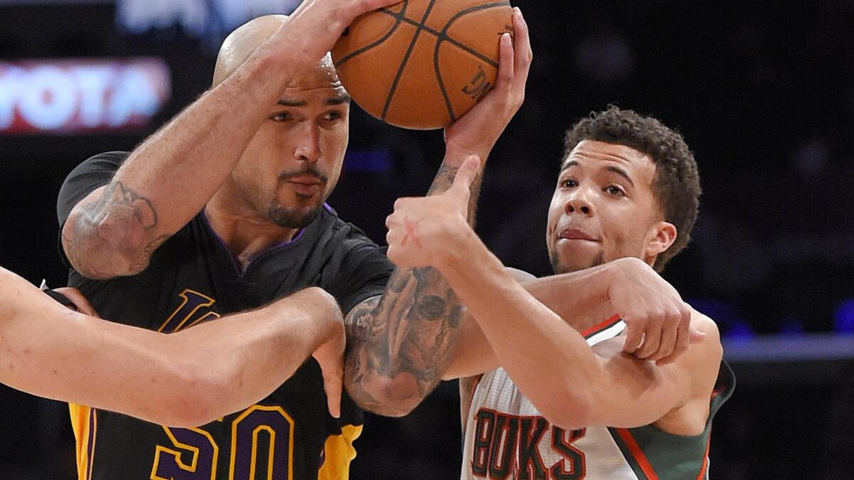 Milwaukee Bucks guard Michael Carter-Williams, left, tries to steal the ball from Lakers center Robert Sacre during the Lakers' win at Staples Center on Feb. 27.