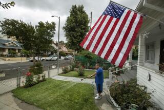 LINCOLN HEIGHTS, CA-MAY 20, 2022: Eddie Vasquez, 61, waters the front lawn of his home on Thomas St. in Lincoln Heights. Vasquez said that he waters the lawn once a week, giving it a good soaking. He has the American flag out in honor of the victims of 9/11 and also because of his nephew, who joined the Marines and is now Staff Sgt. Victor Martinez. It's going to be a summer of brown grass and hard choices for Southern California lawn owners facing the Metropolitan Water District's one day a week watering restrictions starting June 1. (Mel Melcon / Los Angeles Times)