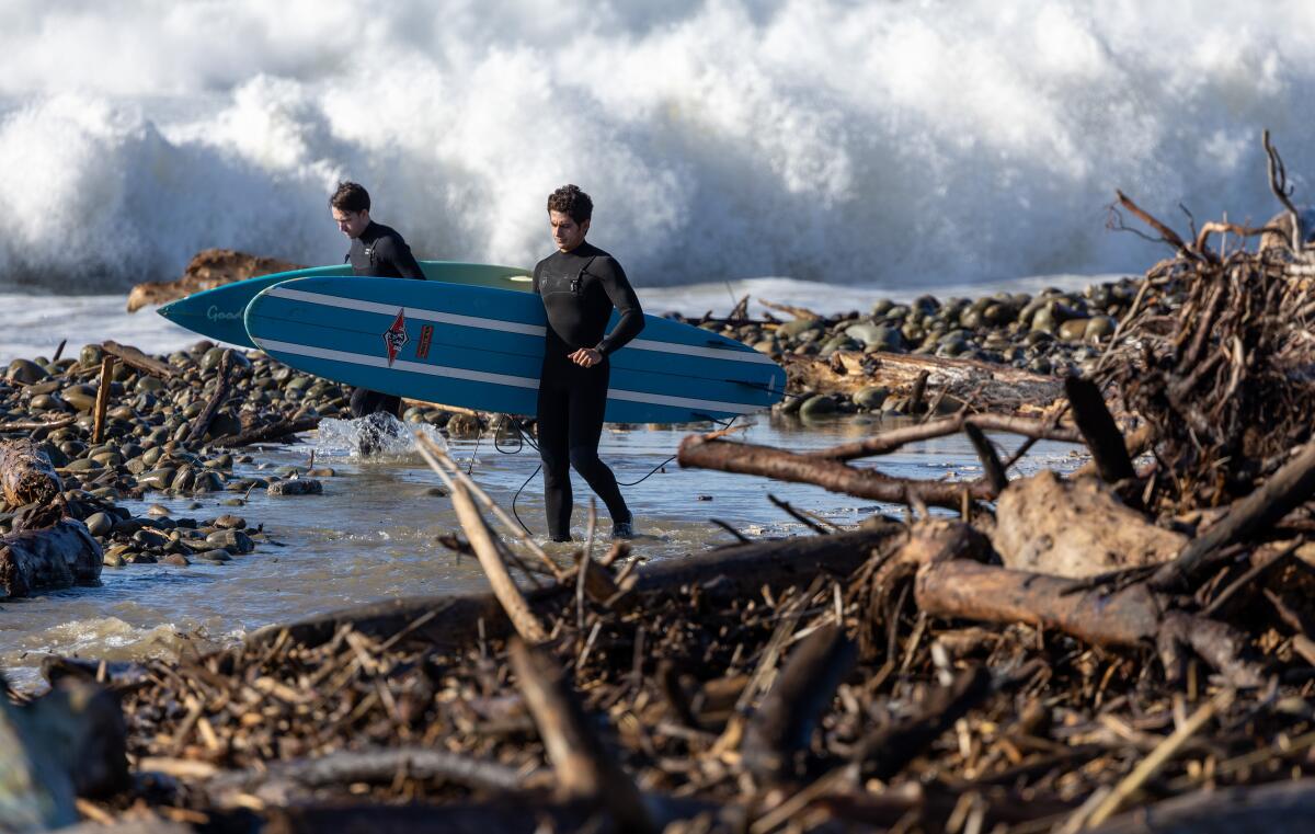 Surfers navigate rocks and driftwood at Surfer's Point as they look for a spot to enter the water