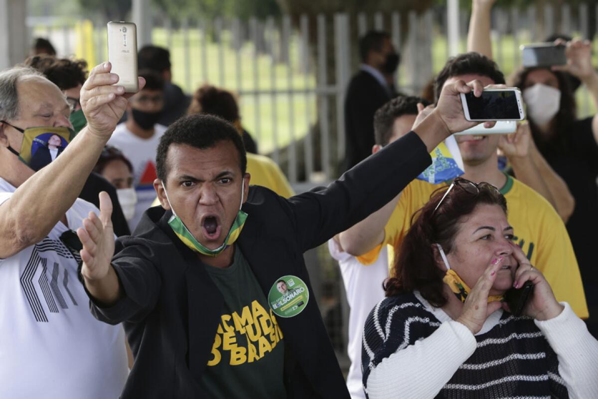 Supporters of Bolsonaro scream at journalists Monday outside the president's official residence in Brasilia.