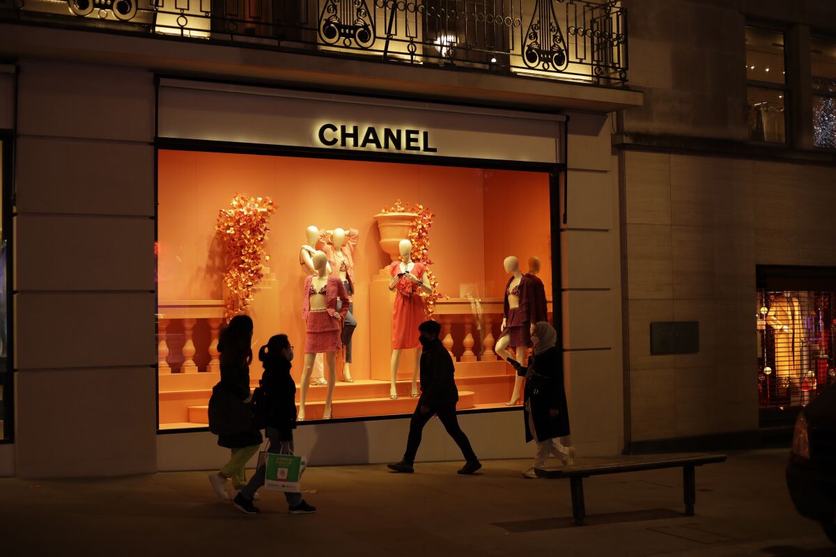 FILE - People walk past the temporarily closed Chanel shop on New Bond Street, during England's second coronavirus lockdown in London, on Nov. 25, 2020. French high fashion brand Chanel says it is stopping selling its clothes, perfumes and other luxury good to Russian customers abroad in a bold response to Moscow’s invasion of Ukraine. (AP Photo/Matt Dunham, File)