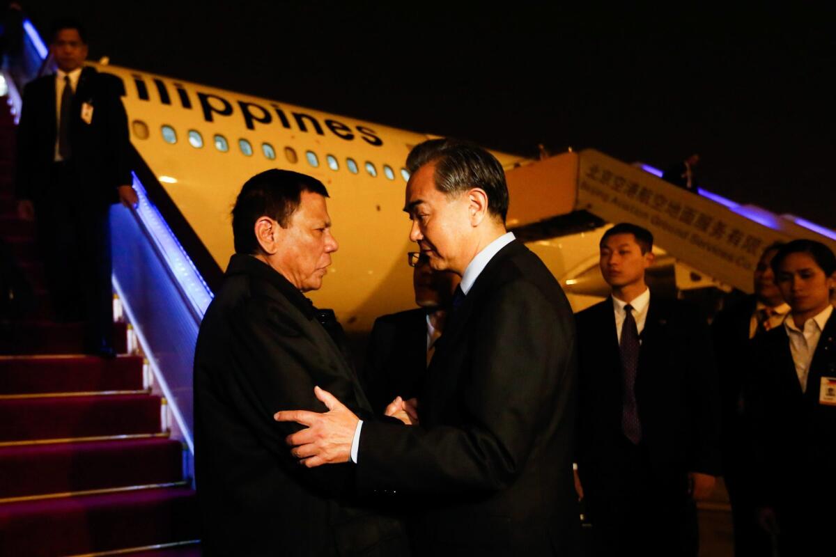 Philippine President Rodrigo Duterte, left, greets Chinese Foreign Minister Wang Yi as Duterte arrives in Beijing on Oct. 19, 2016.