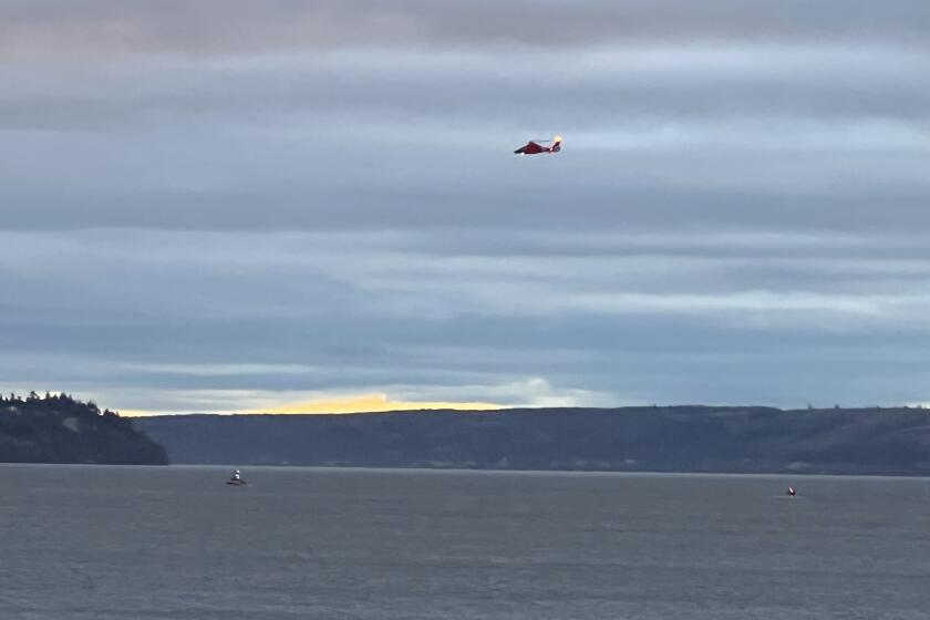 A Coast Guard helicopter searches the area where a floatplane crashed near Whidbey Island, Wash., Sunday, Sept. 4, 2022. (Courtney Riffkin/The Seattle Times via AP)