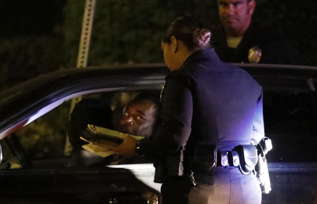 LAPD officers give a man a ticket for an expired registration in South Los Angeles on July 25, 2019.