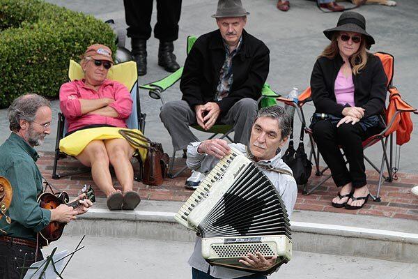 Peter Gach, a professor of music at Palomar College in San Marcos, Calif., plays "In C" on the accordion at the Village Faire Shopping Center in Carlsbad. About 15 musicians joined him to play the 40-minute Terry Riley composition in the open-air courtyard as part of the three-day Carlsbad Music Festival in the north San Diego County coastal city.