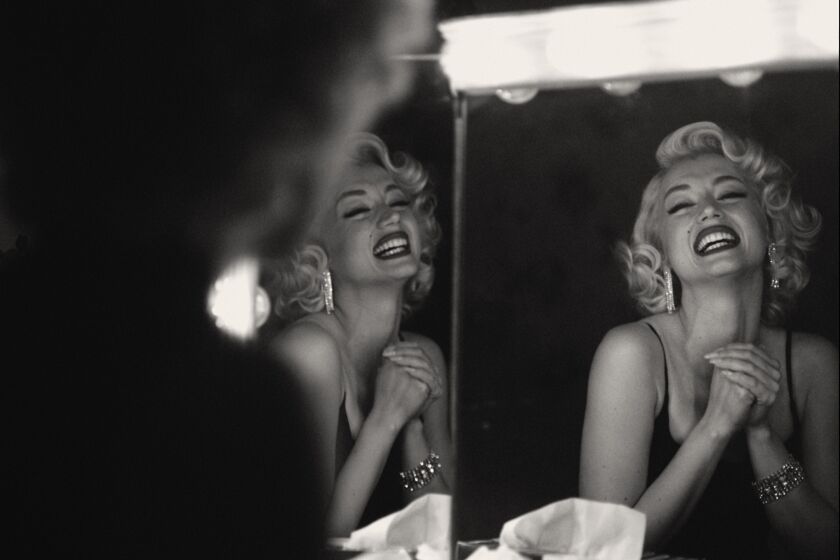 A black-and-white image of a blond woman smiling into a mirror