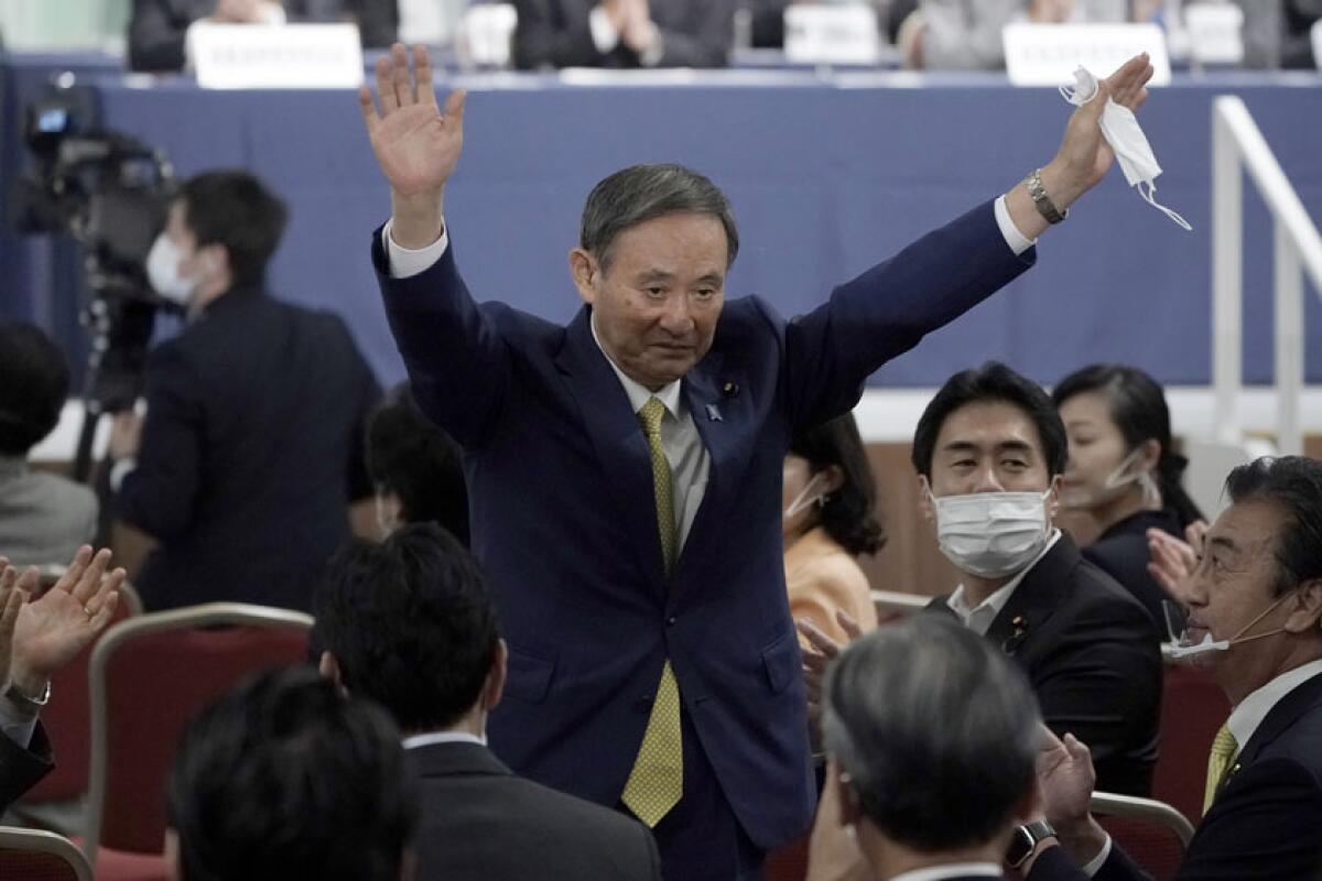 Japanese Chief Cabinet Secretary Yoshihide Suga acknowledges applause after winning a party vote on Monday.