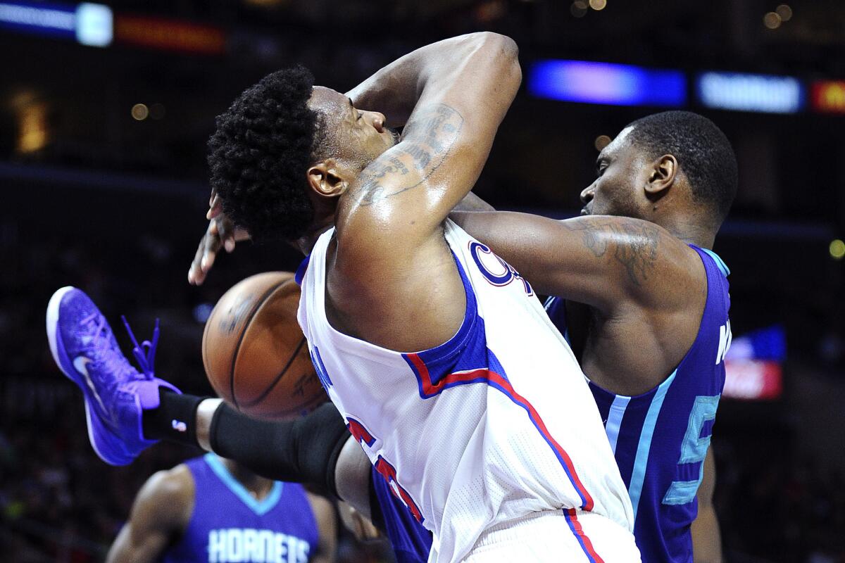 The Clippers' DeAndre Jordan and the Hornets' Jason Maxiell fight for a rebound during a game Tuesday at Staples Center.
