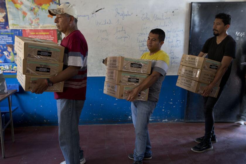 Electoral volunteers unload boxes filled with ballots at a polling station at a school on the outskirts of San Salvador, El Salvador, Friday, Feb. 1, 2019. Salvadorans elect a new president on Sunday. (AP Photo/Moises Castillo)