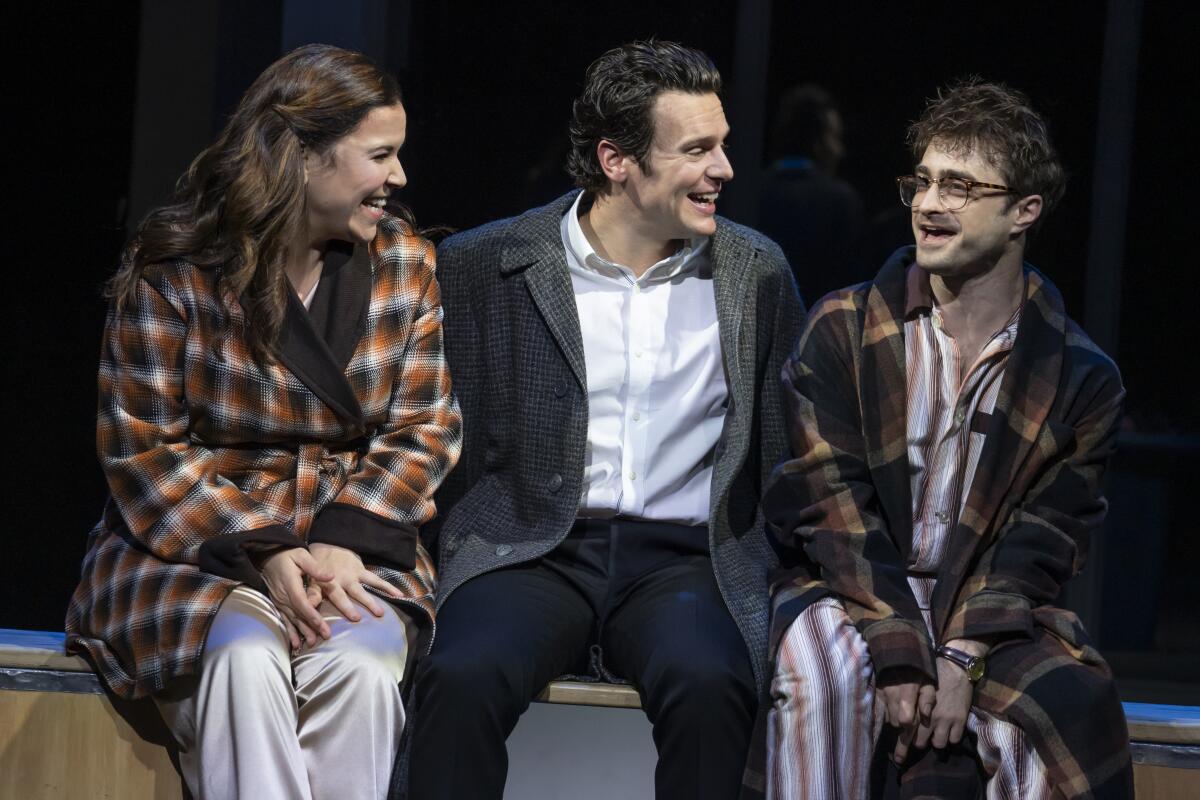 Three actors seated onstage.