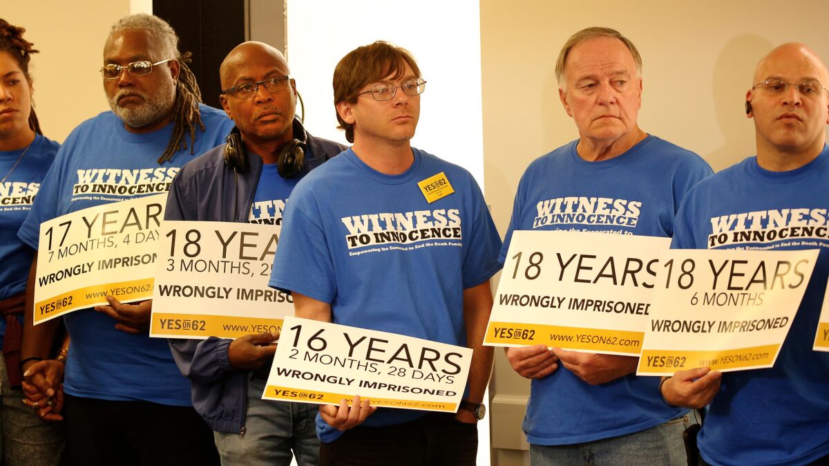 Death row exonerees from across the nation hold signs showing the number of years they were wrongly imprisoned as they listen to Mike Farrell at a Prop. 62 campaign event. (Al Seib / Los Angeles Times)
