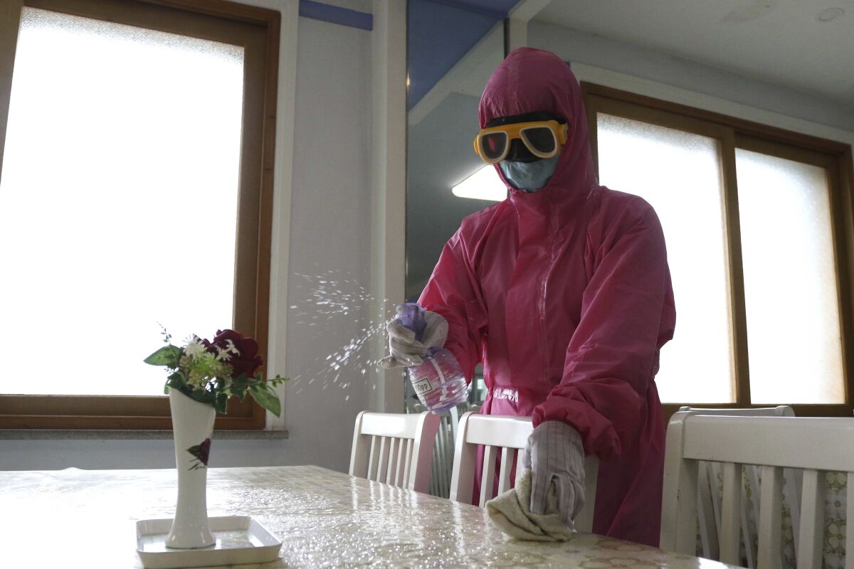 An employee in full protective gear disinfects the floor of a dining room in North Korea