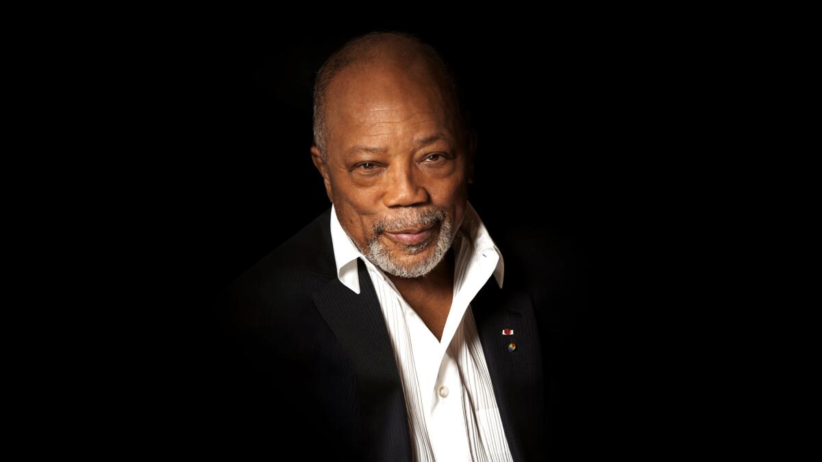 Quincy Jones in a white collared shirt and black suit jacket. 