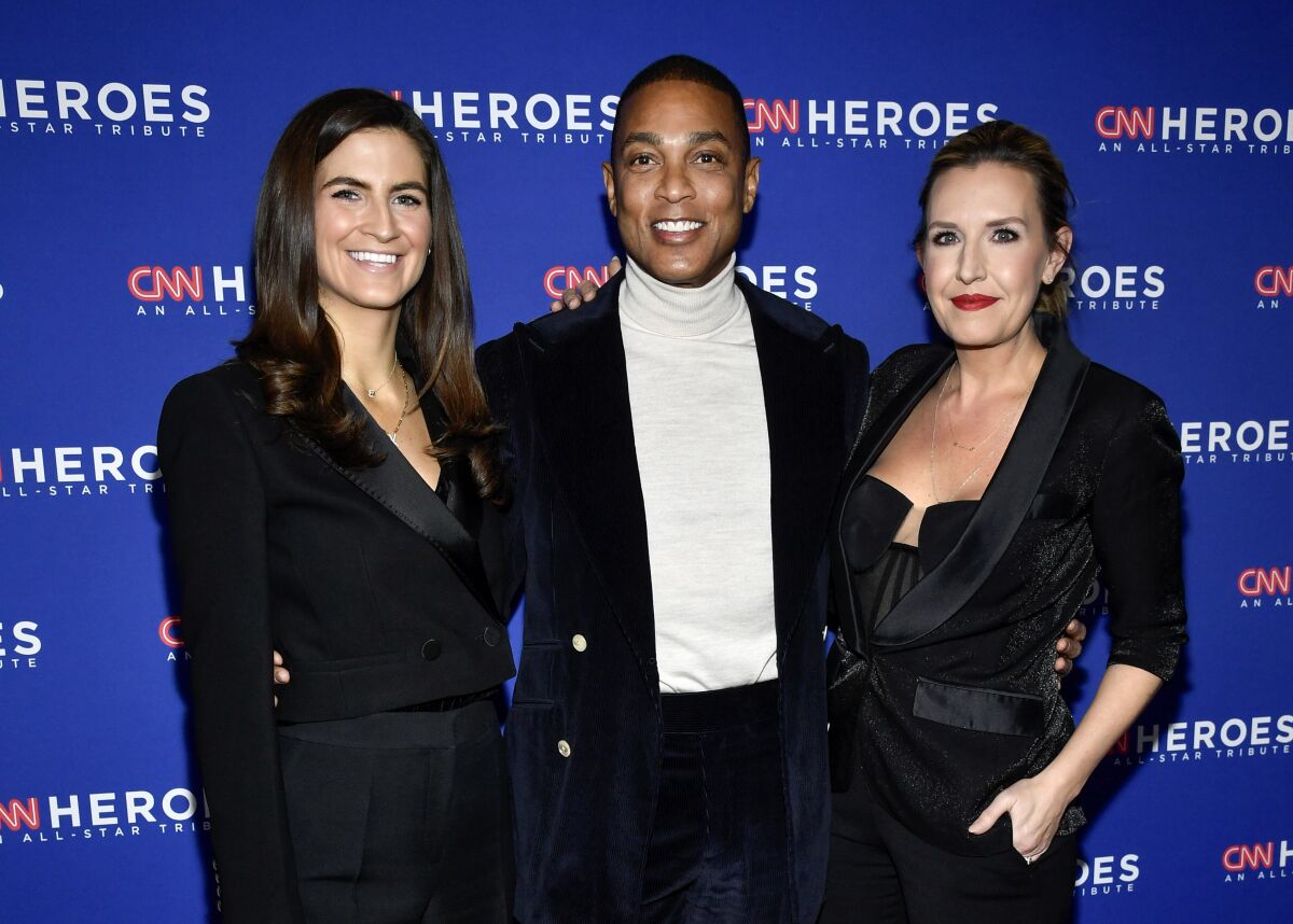 A man and two woman stand before a step-and-repeat