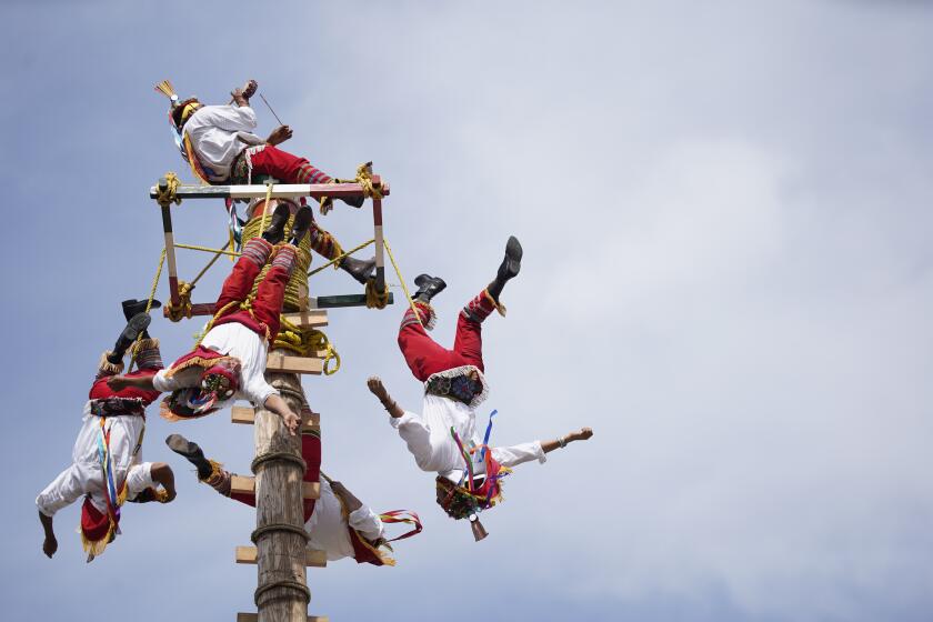 Tijuana, Baja California - September 27: Sitting on top of 100 foot pole Crisanto de Leon Salazar plays music while the dancers lean back and fall backwards, spinning around the pole as they descend. Los voladores de Papantla (The Flyers of Papantla) the traditional Mexican dance ritual performed at the Centro Cultural Tijuana on Wednesday, Sept. 27, 2023 in Tijuana, Baja California. (Alejandro Tamayo / The San Diego Union-Tribune)