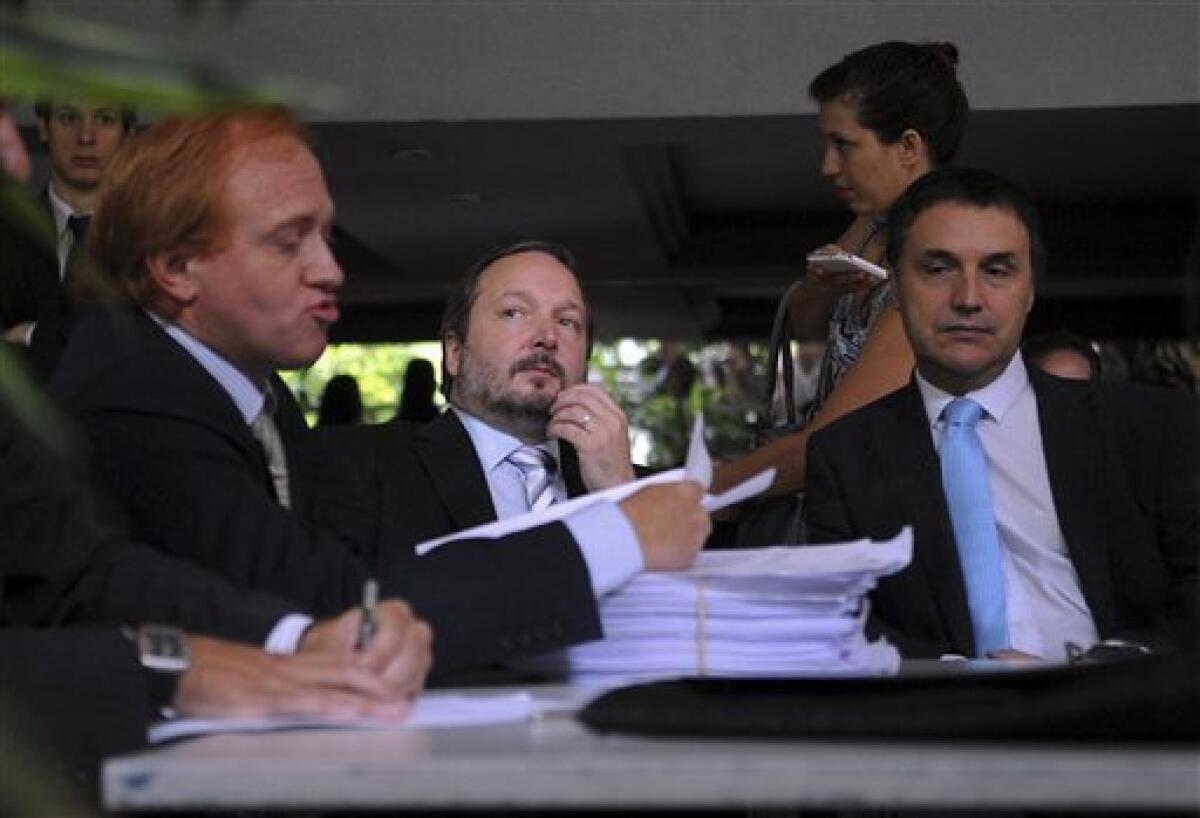 Martin Sabbatella, center, head of the government media regulation body, Federal Authority on Audiovisual Communication Services (AFSCA) and Sergio Surano, right, director of the AFSCA legal department, listen as Grupo Clarin's lawyer Damian Cassino, left, speaks during a meeting, in Buenos Aires, Argentina, Monday, Dec. 17, 2012. Sabbatella said Monday that the government will make the conglomerate and other companies comply with the law, which bars any company from owning too many different media properties. The law could require Grupo Clarin to sell off broadcast licenses as well as its majority stake in Cablevision, the cable TV network that has become the company's cash cow. (AP Photo/Daniel Dabove,Telam)