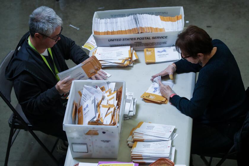 Santa Ana, CA - November 09: Brant Taketa, left, and Christine Celio sort envelopes containing ballots at Vote-By-Mail ballot processing center at Orange County Registrar of Voters on Wednesday, Nov. 9, 2022 in Santa Ana, CA. (Irfan Khan / Los Angeles Times)