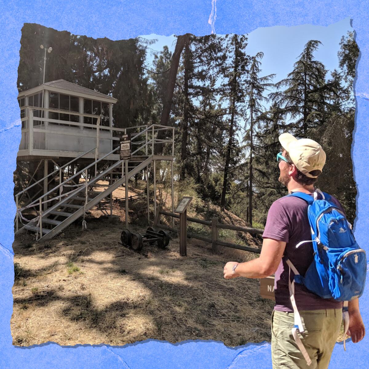 A hiker with a backpack looks at an old forest lookout station. 