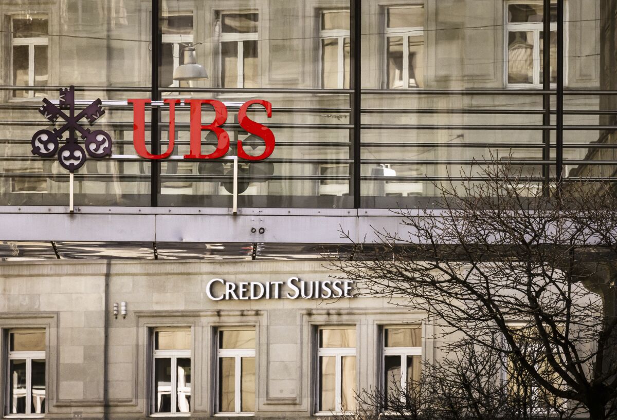 Logos of the Swiss banks Credit Suisse and UBS are seen on two buildings in Zurich, Switzerland, Saturday, March 18, 2023. (Michael Buholzer/Keystone via AP)