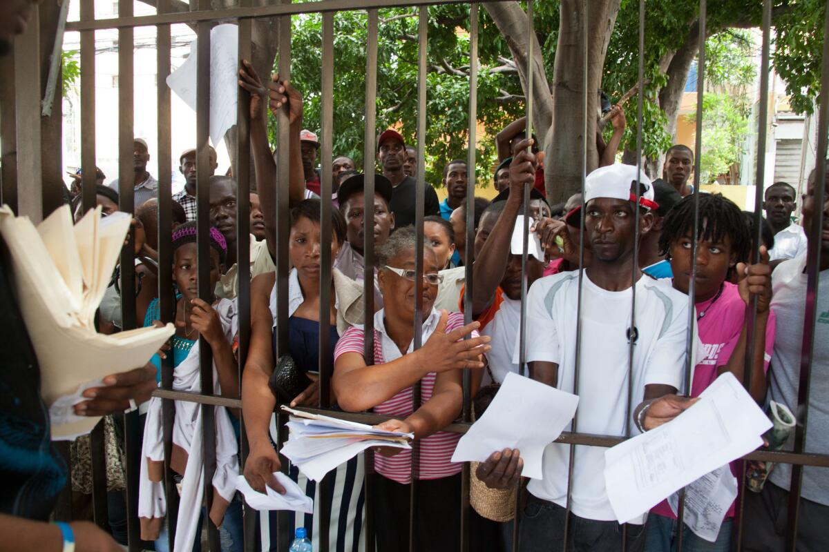 Migrantes, principalmente haitianos, exhiben sus documentos a funcionarios mientras esperan registrar su residencia legal en el ministerio del Interior en Santo Domingo, República Dominicana, el martes 16 de junio de 2015. El gobierno dominicano se prepara para comenzar esta semana a repatriar inmigrantes que no se hayan registrado en un programa especial para legalizar su estatus, mientras miles de personas hacen largas filas para tratar de inscribirse.