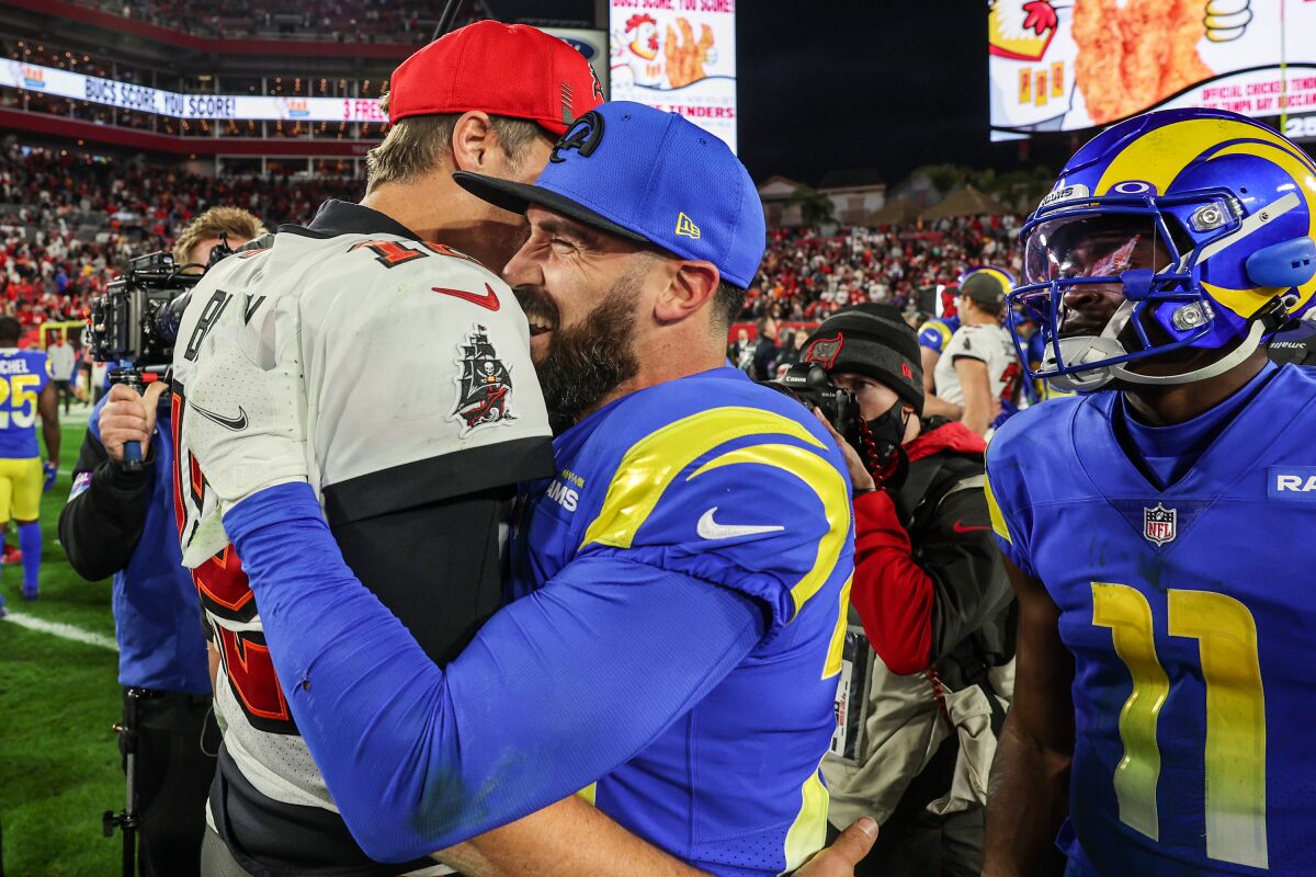 Rams safety Eric Weddle, right, embraces Buccaneers quarterback Tom Brady.