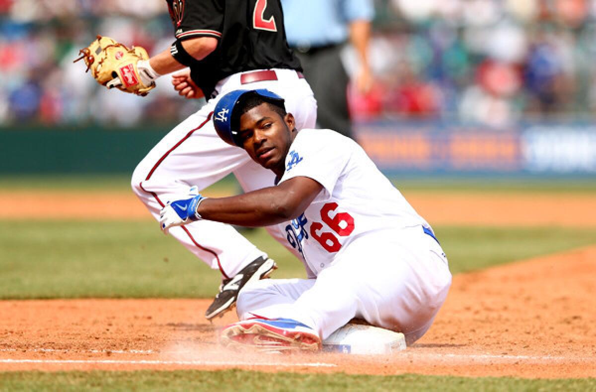 Dodgers right fielder Yasiel Puig slides back to first base after being tagged out by Diamondbacks second baseman Aaron Hill while in a rundown during a game Sunday in Sydney, Australia.