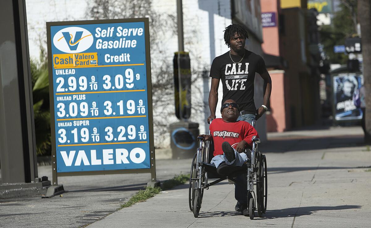 Vincent Cowart, top, and his brother Eddie Peterson of Los Angeles, make their way past a sign showing the prices of gas at a Valero gas station on Van Nuys Boulevard in Van Nuys. Wholesale gas prices rose 6 to 10 cents in California after a large refinery explosion.