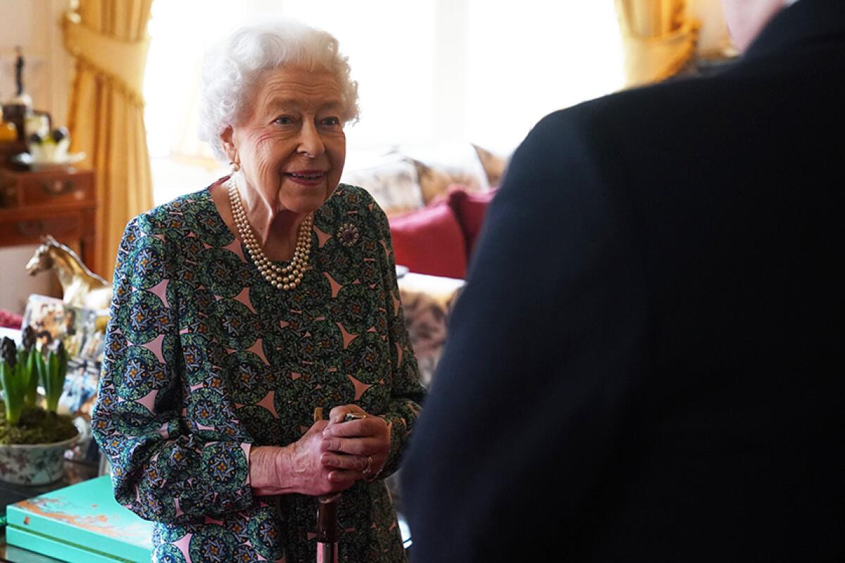 Queen Elizabeth II smiles at a visitor.