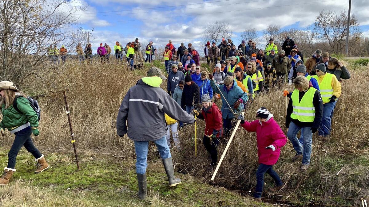 Volunteers cross a creek and barbed-wire fence near Barron, Wis., during the search for 13-year-old Jayme Closs on Oct. 23.