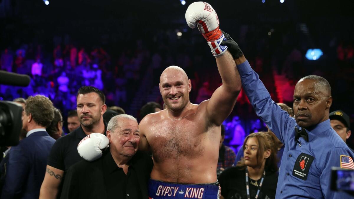 Tyson Fury, center, poses with boxing promoter Bob Arum, left, and referee Kenny Bayless after defeating Tom Schwarz during a heavyweight fight on Saturday in Las Vegas. Fury won with a second-round TKO.