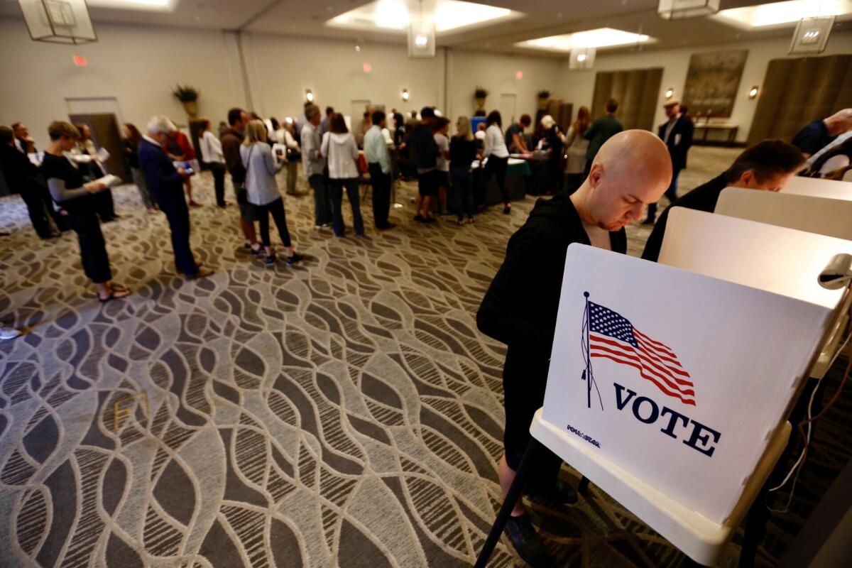 Luke Hallberg casts his ballot as voters stand in line at the Luxe Sunset Boulevard Hotel polling station in Brentwood.