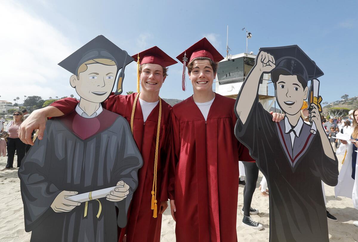 Twin brothers Jack and Sam Arntz stand with life-size cardboard cutouts of themselves on the sand at Main Beach.