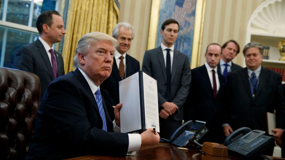 President Trump shows off a signed executive order reinstating a ban on funding for international organizations that provide abortion services or related counseling. (Evan Vucci / Associated Press)