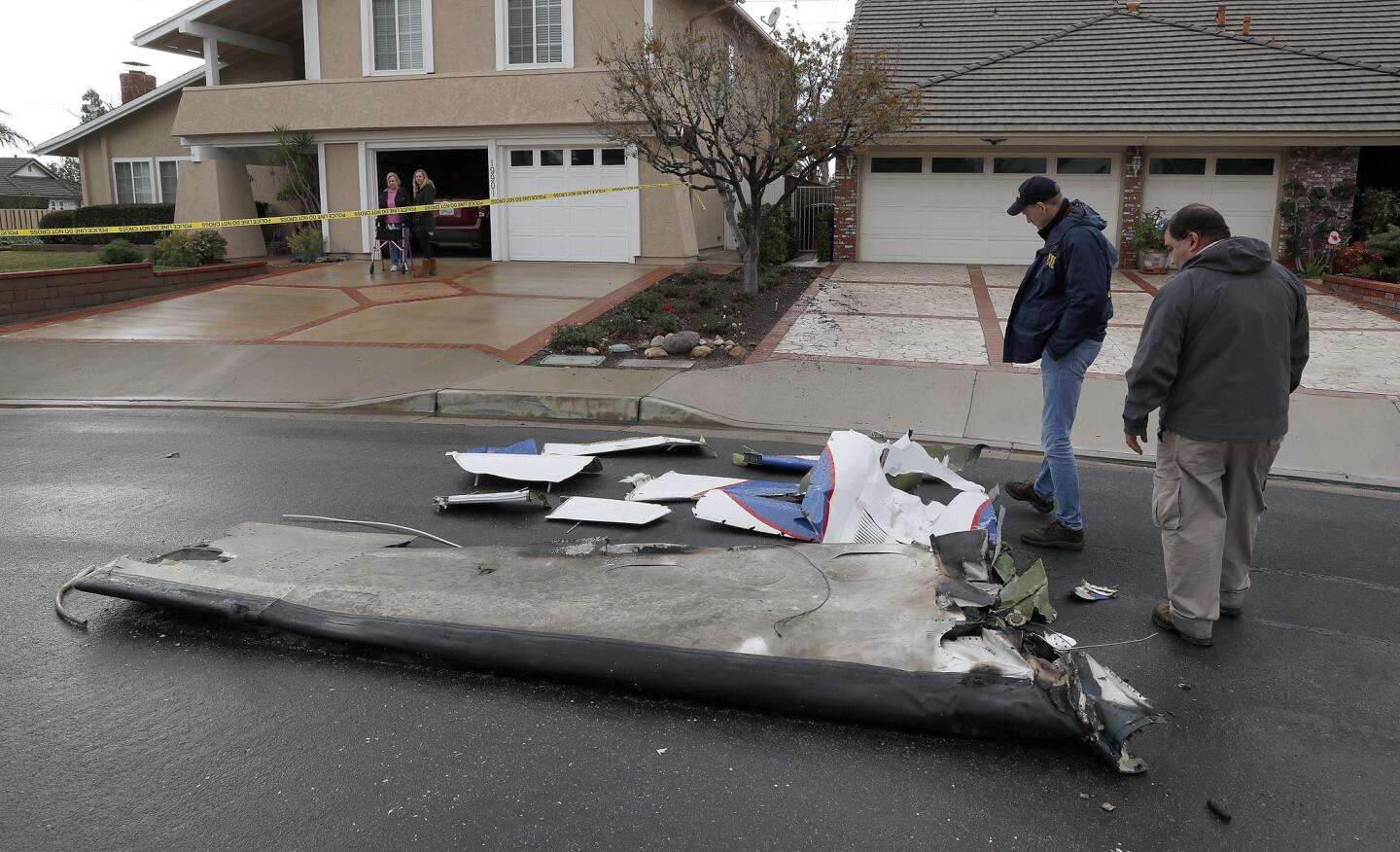 Peter Knudson, a media relations specialist with the National Transportation Safety Board, left, and air safety investigator Ricardo Asensio review pieces of a Cessna airplane that crashed into a Yorba Linda home. Five people, including pilot Antonio Pastini, were killed.