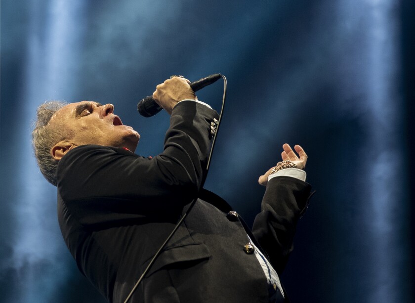 A man in a black jacket sings onstage