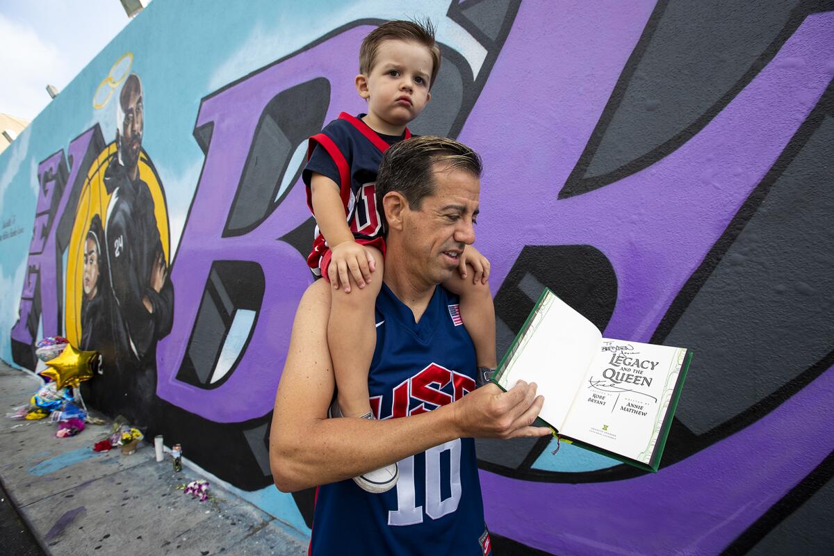 Ryan Broccolo and his son, Brayden, show off a signed copy of Kobe Bryant's book "Legacy and the Queen" on Monday.