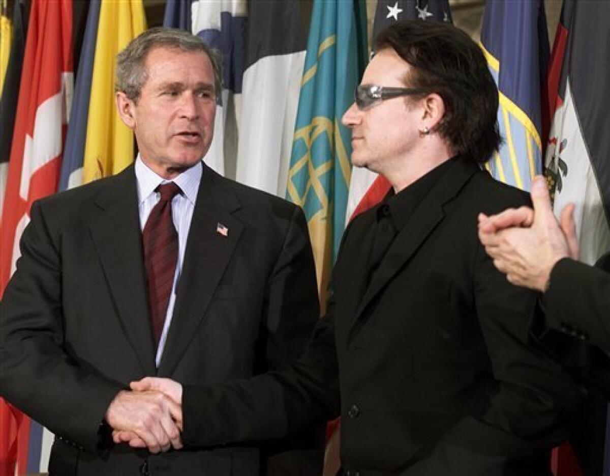 FILE - This is a Thursday, March 14, 2002 file photo of President Bush as he shakes hands with Bono, right, lead singer of the Irish rock group U2, after Bush spoke at the Inter-American Development Bank, in Washington. (AP Photo/Ron Edmonds)