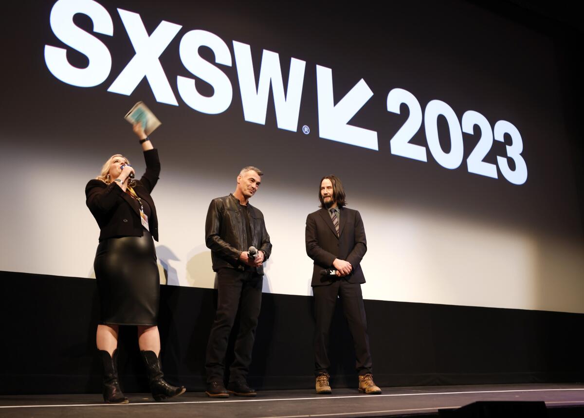 Claudette Godfrey, left, Chad Stahelski and Keanu Reeves on stage