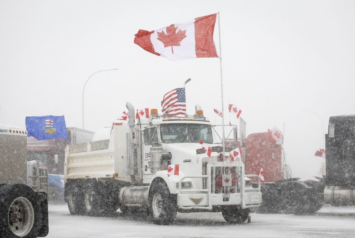 Anti-COVID-19 vaccine mandate demonstrators gather as a truck convoy blocks the highway at the busy U.S. border crossing in Coutts, Alberta, Canada, Monday, Jan. 31, 2022. Thousands of antivaccine protesters descended on Canada’s capital of Ottawa in frigid temperatures to protest vaccine mandates, masks and restrictions over the weekend and some remain, blocking traffic around Parliament Hill in what has been the biggest pandemic protest in the country to date.(Jeff McIntosh/The Canadian Press via AP)
