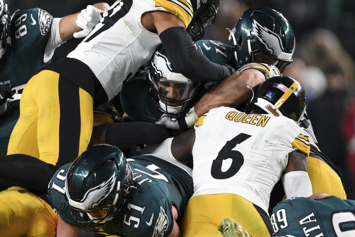 Eagles quarterback Jalen Hurts squeezes his head through a wall of Eagles and Steelers players to get a first down
