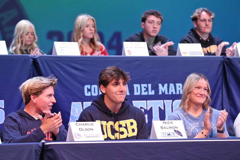 Charlie Olson (golf, Gonzaga University), Nick Salmon (baseball, UCSB), and Abigail Schalow (field hockey, St. Louis College), from left, join others during an overall ovation during annual National Letter of Intent signing day at the Sea King Theater at Corona del Mar High on Monday.