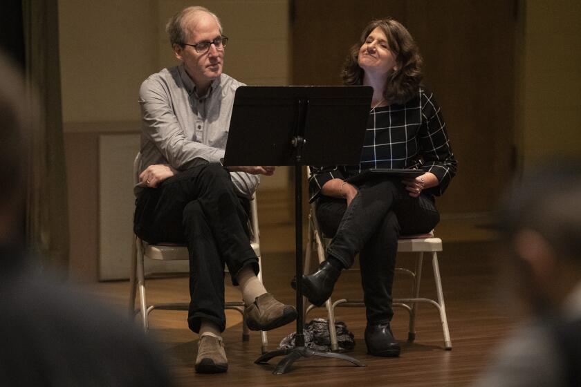 GLENDALE, CALIF. -- WEDNESDAY, JANUARY 15, 2020: Composer Jeff Beale, left, with wife Joan, right, look over the music score as the Los Angeles Master Chorale rehearses Beale’s “Sunrise: A Song of Two Humans" to in Glendale, Calif., on Jan. 15, 2020. (Brian van der Brug / Los Angeles Times)