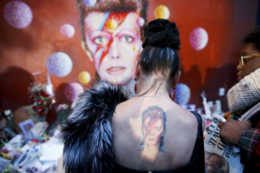 A woman with a Ziggy Stardust tattoo visits a mural of David Bowie in Brixton, south London, January 11, 2016. David Bowie, a music legend who used daringly androgynous displays of sexuality and glittering costumes to frame legendary rock hits "Ziggy Stardust" and "Space Oddity", has died of cancer. REUTERS/Stefan Wermuth TPX IMAGES OF THE DAY ** Usable by SD ONLY **